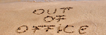 Out of office text written on the beach sand